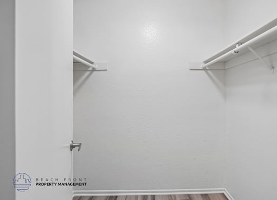 A white closet with a shelf and a logo for Beach Front Property Management.