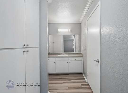 A white bathroom with a mirror and wooden floors.