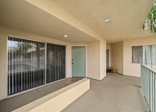 A balcony with a green door and a bench inside a room.