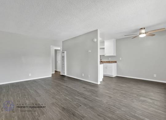 A spacious room with wooden flooring and a ceiling fan.