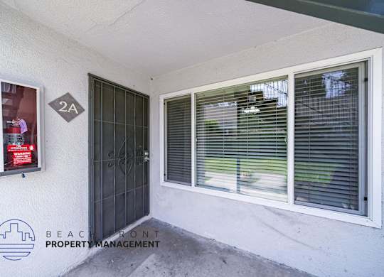A white wall with a window and a door with a sign on it.