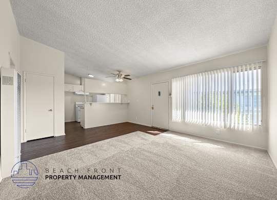 A spacious room with a carpeted floor and a ceiling fan.