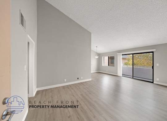 the living room and dining room of an apartment with wood flooring and a balcony