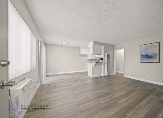 A spacious room with wooden flooring and a white cabinet.
