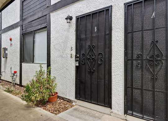 A black gate with a decorative design is on the right side of a white building.