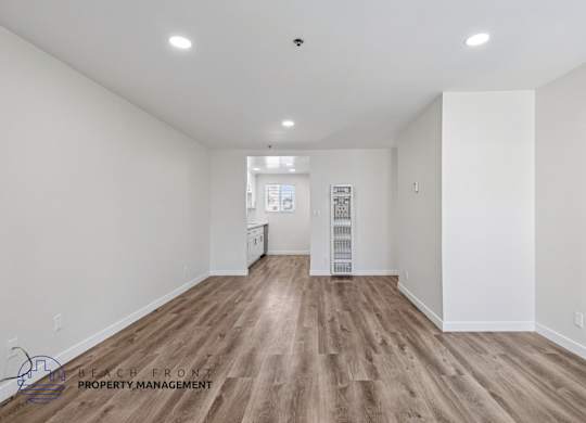 A spacious room with wooden flooring and white walls.