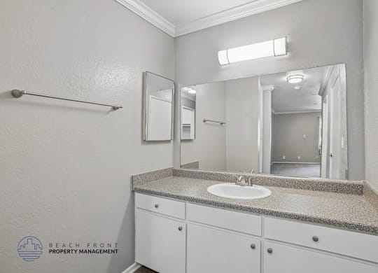 A bathroom with a sink, mirror, and cabinets.