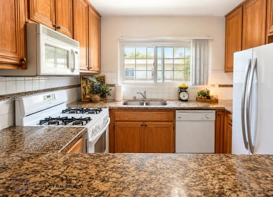 A kitchen with granite countertops and white appliances.