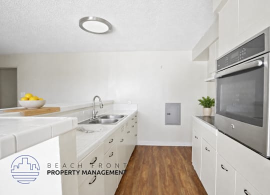 A modern kitchen with white cabinets and a stainless steel oven.