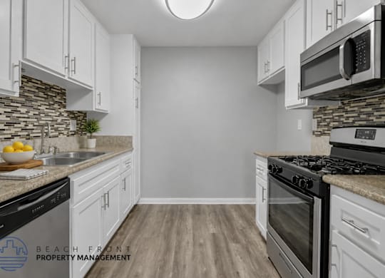 A kitchen with white cabinets and a stone backsplash.