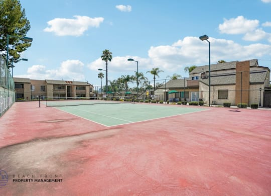 A tennis court with a red surface and a logo of