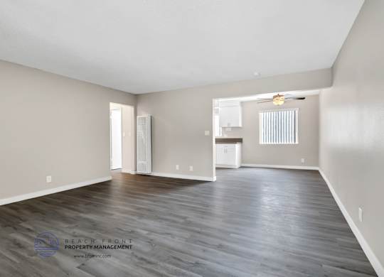 A spacious room with wooden flooring and a large window.
