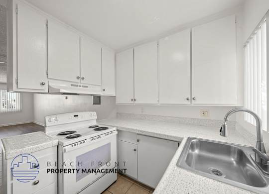 A kitchen with white cabinets and a stove top oven.