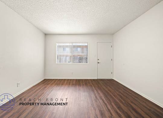 A room with wooden floors and a window with blinds.