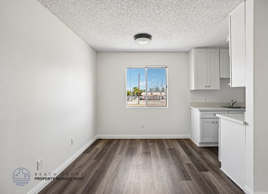 A kitchen with white cabinets and a wooden floor.