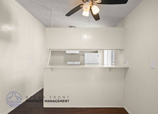 A room with a ceiling fan and a logo for Beach Front Property Management.