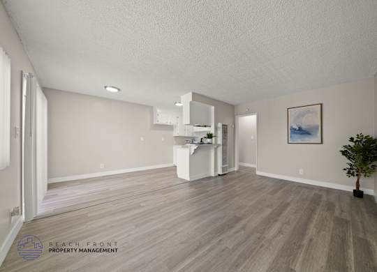 A spacious room with wooden flooring and a white cabinet.