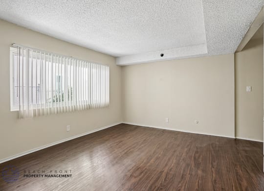 A room with wooden floors and a window with blinds.