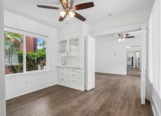 A spacious room with a ceiling fan and wooden flooring.