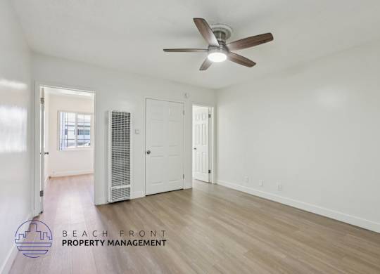 A spacious room with a ceiling fan and wooden flooring.