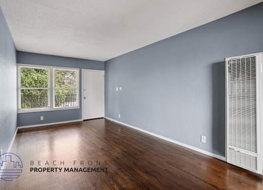 A room with a window and a wall-mounted air conditioning unit.