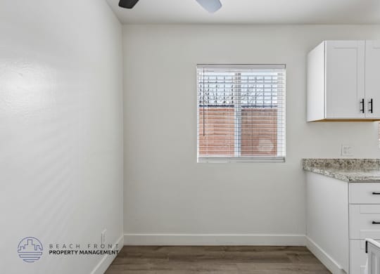 A kitchen with white cabinets and a marble countertop.