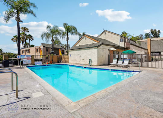 A pool surrounded by a fence and palm trees.