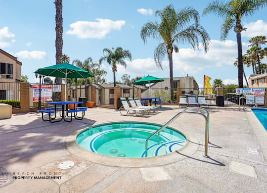 A pool area with a hot tub and lounge chairs.