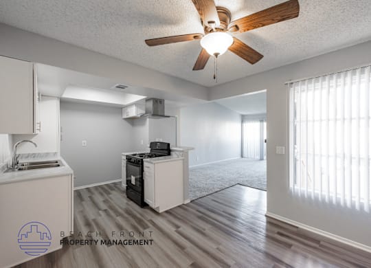 A spacious room with a ceiling fan and a kitchenette.