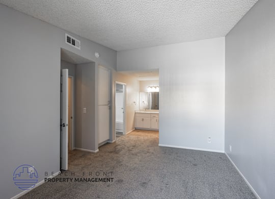 A spacious room with a carpeted floor and a window with blinds.