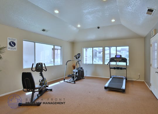 A spacious room with exercise equipment and a logo for Beach Front Property Management.