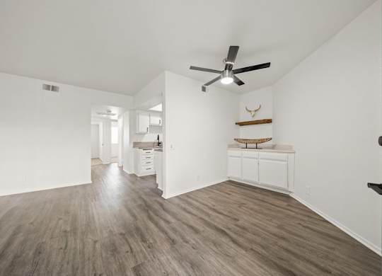 A room with a ceiling fan and wood flooring.