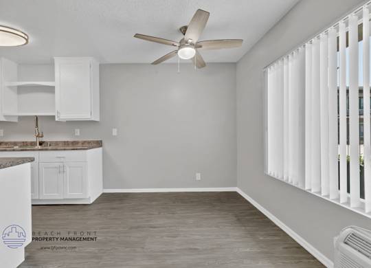 A room with a ceiling fan and a window with blinds.