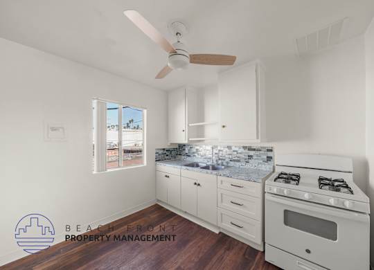 A kitchen with a stove, oven, and a fan.