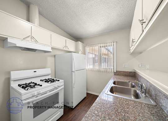 A kitchen with a stove, refrigerator, and sink.