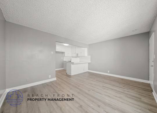 A room with wooden flooring and a logo for Beach Front Property Management.