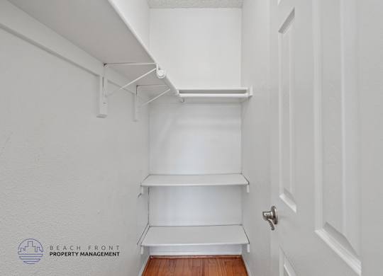 A white hallway with a door and a shelf.