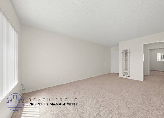A spacious room with carpeted floor and white walls, with a logo for Beach Front Property Management in the bottom left corner.