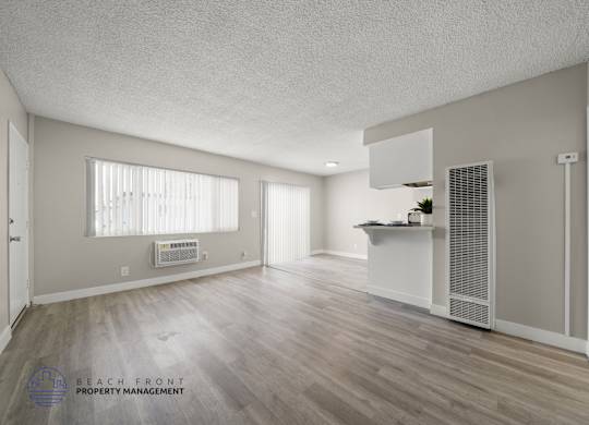 A spacious room with wooden flooring and a white ceiling.