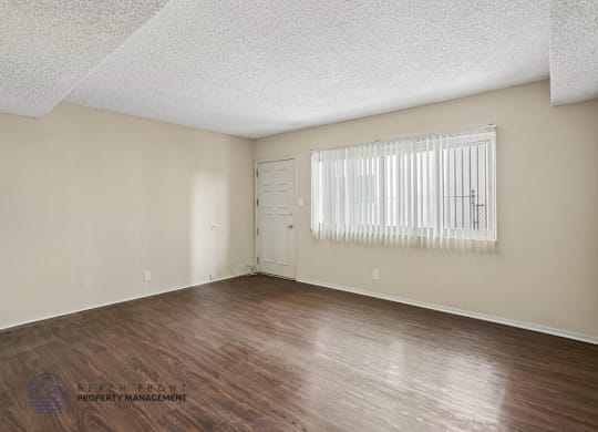 A room with wooden flooring and a window with blinds.