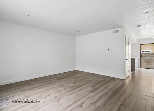 A room with wooden flooring and white walls.