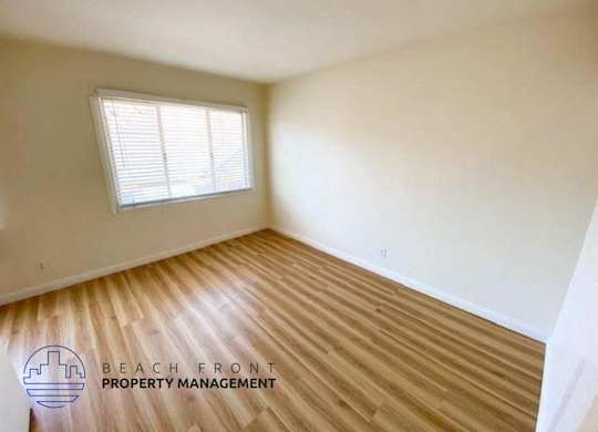 an empty room with wood flooring and a window