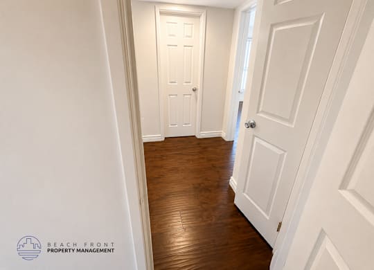 A hallway with white doors and wooden floors.