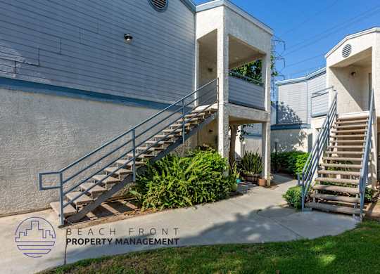 A building with a staircase and a sign that says Beach Front Property Management.