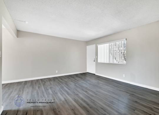 A room with wooden flooring and a window with blinds.