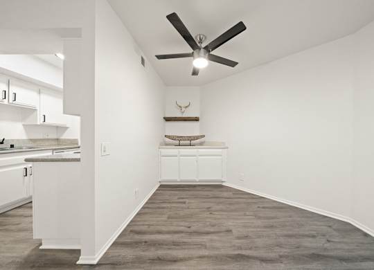 A room with a ceiling fan and a deer head on the wall.