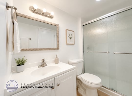 A bathroom with a white toilet, sink, and mirror.