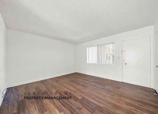the living room of an apartment with vinyl 
plank flooring and white walls