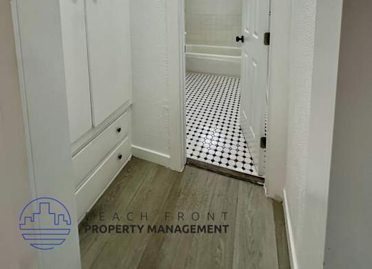 A white bathroom with a mirror and a wooden floor.