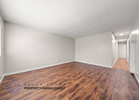 A room with wooden flooring and a logo for Beach Front Property Management.